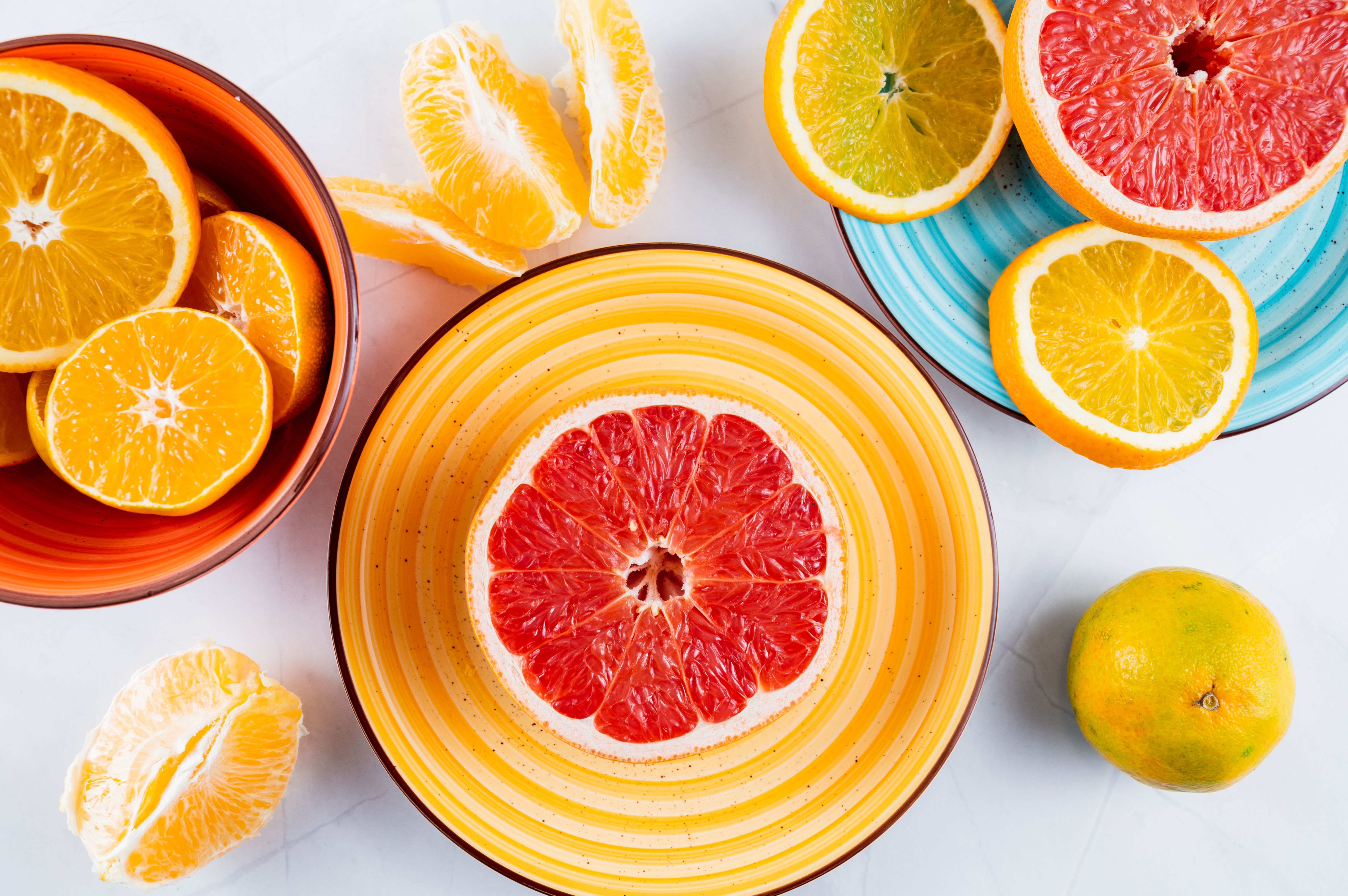 Overhead arrangement of orange and grapefruit slices in colorful dishes, providing a bright example of warm food hues.